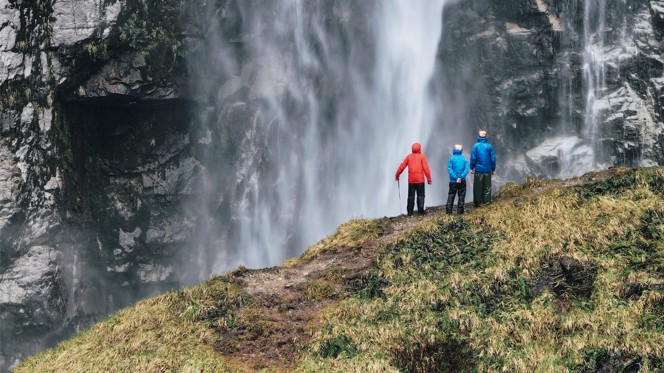 Three hikers enjoying the view of a large water fall in Chile.